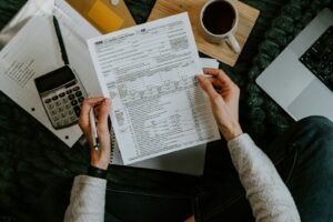 Hands holding tax forms with calculator and laptop